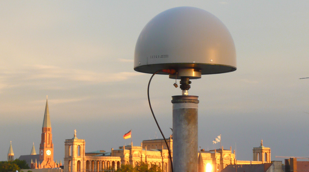 SAPOS-Antenne vor bewölktem Himmel, am unteren Bildrand das Maximilianeum